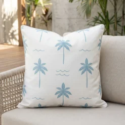 Tropica aqua cushion with palm tree pattern on light outdoor armchair.
