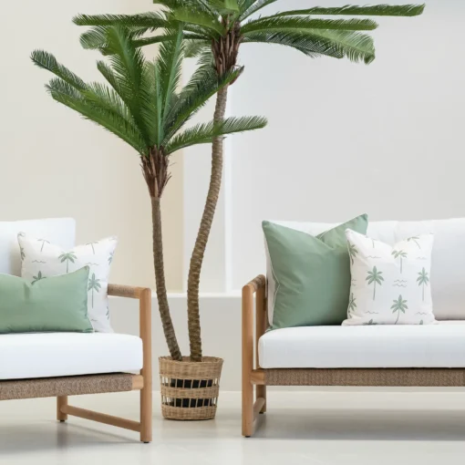 Tropica green cushions styled on outdoor sofa with palm tree backdrop.