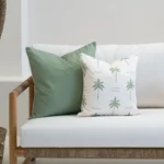 Tropica green cushions with palm print and solid sage on white sofa.