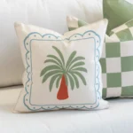 Close-up of Tropica green cushion with palm motif and blue border.