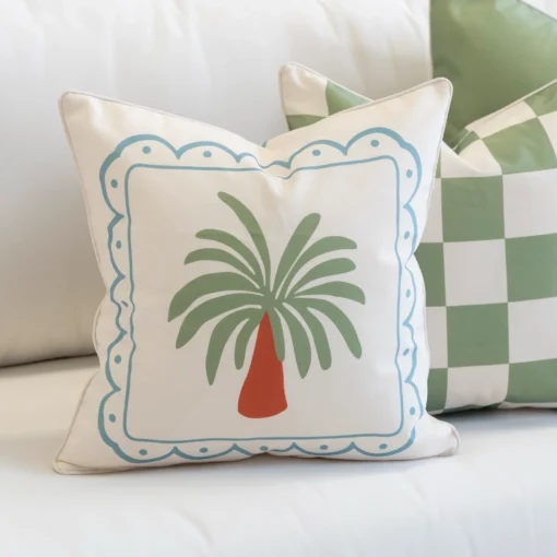 Close-up of Tropica green cushion with palm motif and blue border.