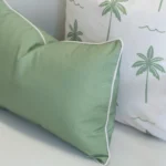Close-up of Tropica green cushion with piping beside palm print cushion.