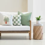 Tropica green cushions set with palm and check designs on outdoor sofa.