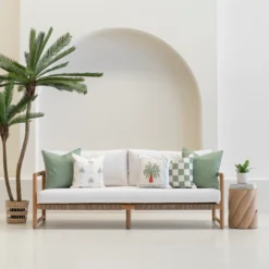Tropica green cushions styled on outdoor sofa with palm and check patterns.