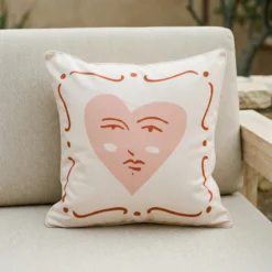 Tropica cushion with pink heart face design on outdoor armchair.