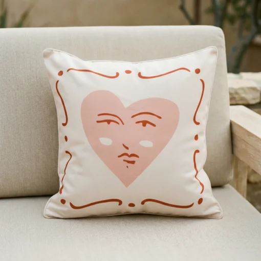 Tropica cushion with pink heart face design on outdoor armchair.