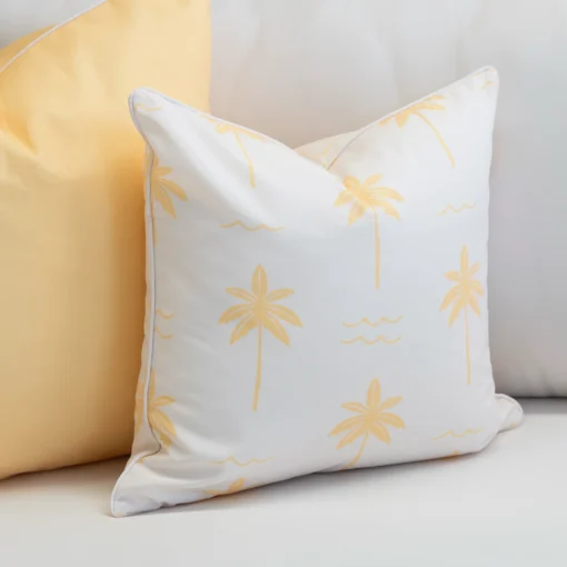 Close-up of Tropica lemon yellow cushion with subtle palm print on white background.