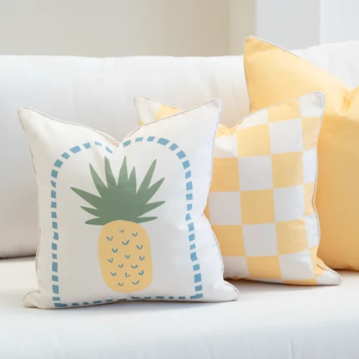 Tropica lemon yellow cushions with pineapple print and gingham pattern on sofa.