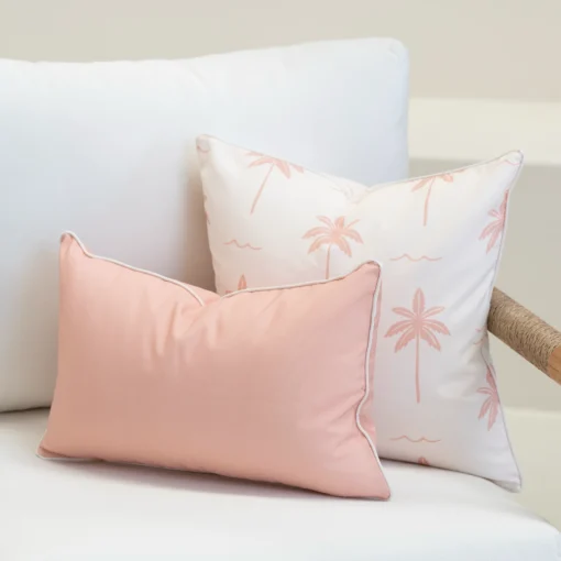 Tropica pink cushions with palm print paired with solid blush rectangular cushion on sofa.