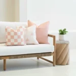 Tropica pink cushions with check and palm patterns on outdoor sofa.