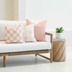 Tropica pink cushions with check and palm patterns on outdoor sofa.