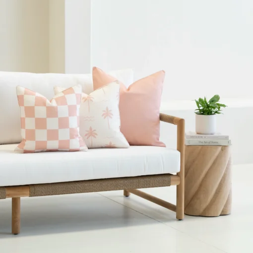Tropica pink cushions with check and palm patterns on outdoor sofa.