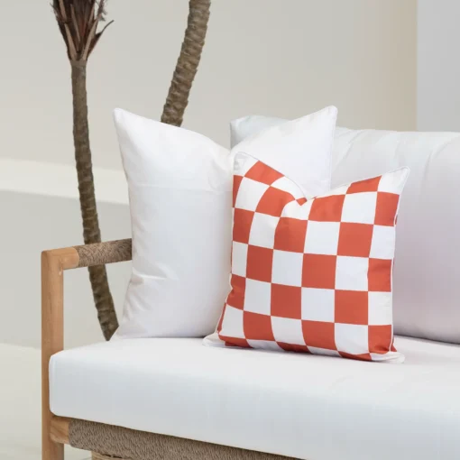 Close-up of Tropica red cushions with bold check pattern and plain white cushions.