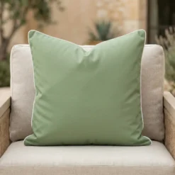 Tropica green cushion with white piping on outdoor armchair.