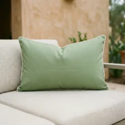 Rectangular Tropica green cushion with white piping on outdoor sofa.