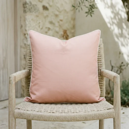 Tropica pink cushion with white piping on woven outdoor chair.