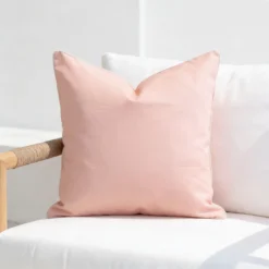 Tropica soft pink cushion with white piping on white outdoor chair.