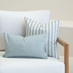 Blue striped and solid Wildgrove Palm cushions arranged on outdoor sofa.