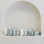 Wildgrove Palm cushions arranged in arched wall nook with soft blue tones.