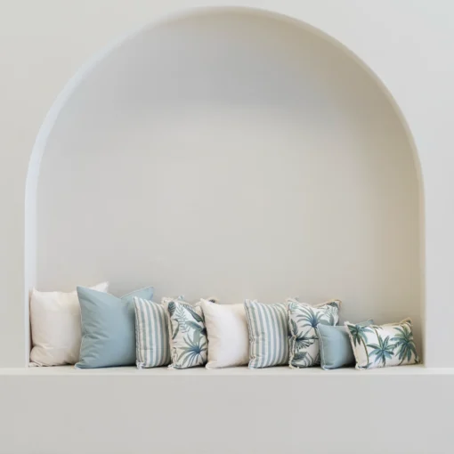 Wildgrove Palm cushions arranged in arched wall nook with soft blue tones.