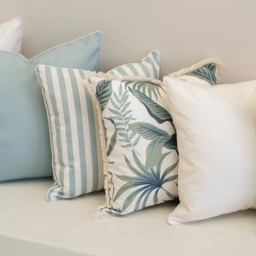 Close-up of Wildgrove Palm cushions with striped and leafy patterns.