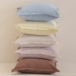 Pastel linen cushions stacked vertically with soft blue, yellow and neutral shades.