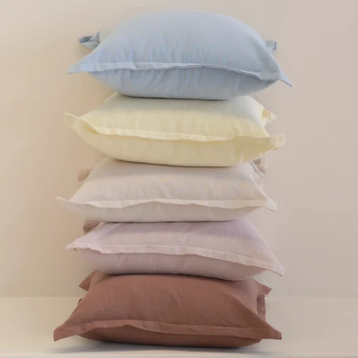Pastel linen cushions stacked vertically with soft blue, yellow and neutral shades.