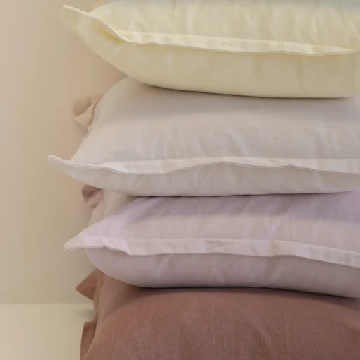Close-up of stacked linen cushions showing soft pastel colours and textured fabric.