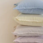 Close-up of stacked linen cushions showing soft pastel colours and textured fabric.